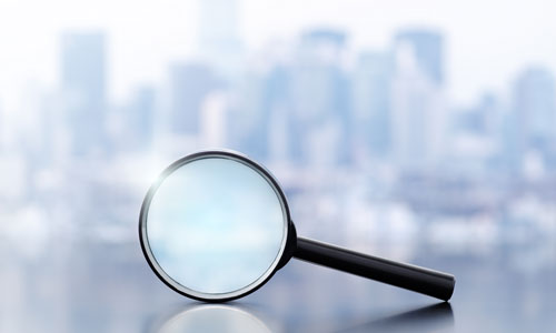 A magnifying glass looking towards a blurred background of a city.