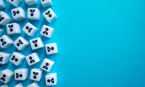 a group of plastic white dice with black icons on a blue background representing workers.
